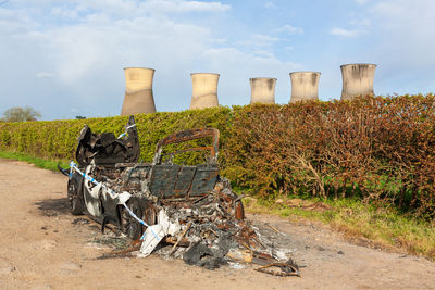 A burned out car in a layby near willington derbyshire with disused colling towers in background.