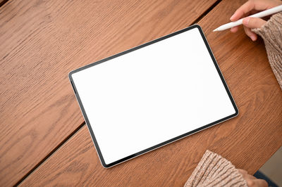 Cropped hands of woman using digital tablet on table