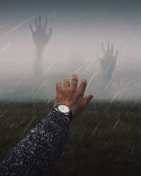 Close-up of male hand against rain