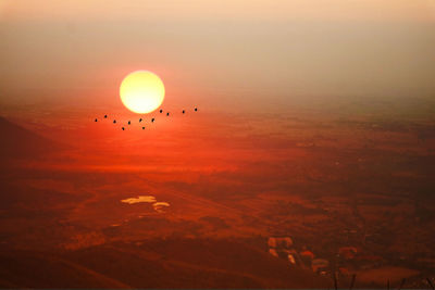 Scenic view of silhouette birds flying against sky during sunset