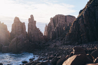 Rock formation at sea against sky