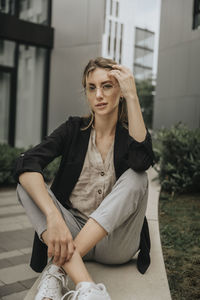 Beautiful young woman sitting with legs crossed at ankle on ledge