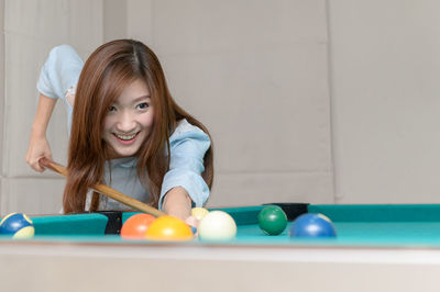 Smiling woman playing at pool table