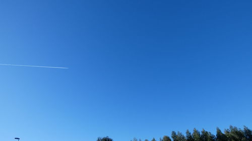 Low angle view of vapor trail against clear blue sky