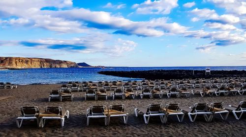 Chairs and tables on beach against sky