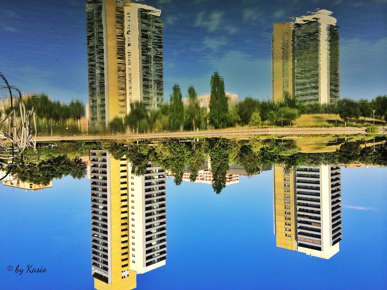 building exterior, architecture, blue, built structure, clear sky, reflection, skyscraper, tall - high, growth, tree, city, low angle view, modern, sky, tower, tall, day, no people, water, outdoors