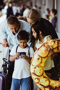 Boy showing camera to family while waiting at train station