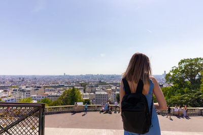 Rear view of woman looking at cityscape against sky