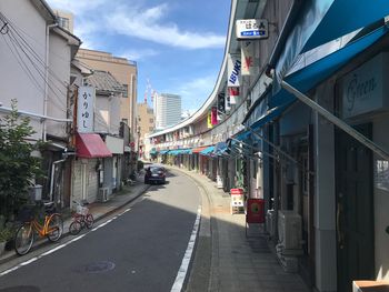 Road amidst buildings in city against sky