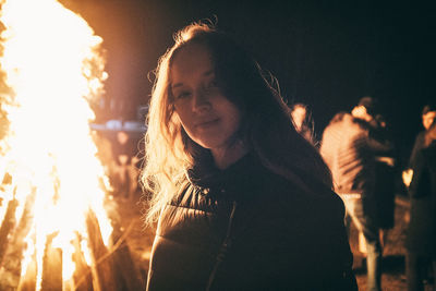 Portrait of young woman standing against sky at night