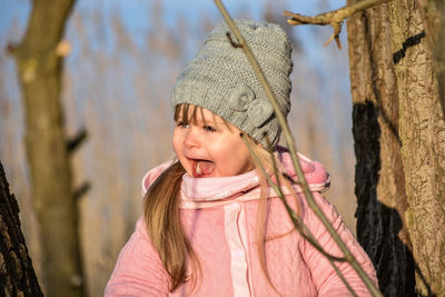 Cute girl screaming while standing by tree