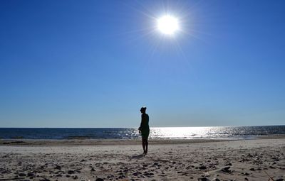 Woman standing on beach against clear sky