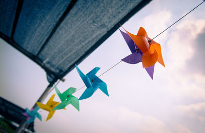 Low angle view of paper toy hanging against sky