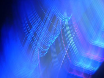 Full frame shot of illuminated light trails on blue background