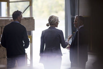 Rear view of business woman discussing with colleagues while standing at lumber industry