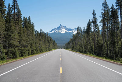 Road amidst trees and mountains against sky