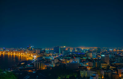 High angle view of illuminated city buildings against clear blue sky