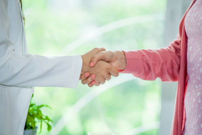 Close-up of hand holding hands against window