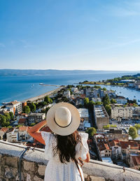 Rear view of woman standing on viewpoint above seaside town of omiš in croatia during summer holiday