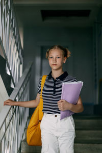 Portrait of young woman standing against building