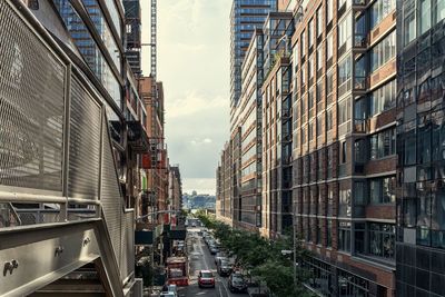 Cars on road by buildings in city against sky