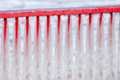 Close-up of frozen red railing during winter