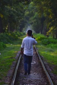 Rear view of man walking on railroad track