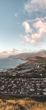 Aerial view of city by sea against sky