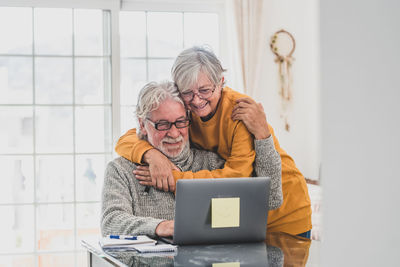 Smiling couple embracing while talking on video call at home