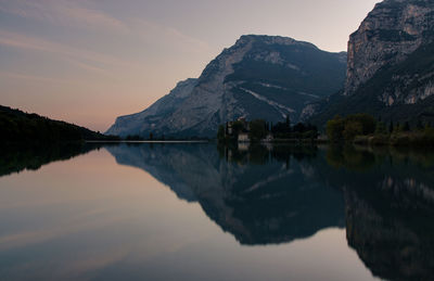 Scenic view of calm lake with mountains reflection at sunset