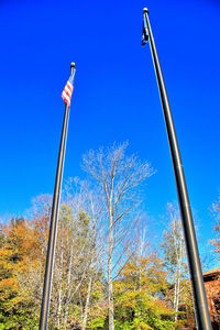 Low angle view of flags against clear blue sky