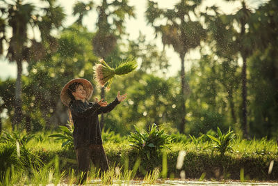 Woman standing by plants on field