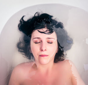 High angle view of woman with eyes closed relaxing in bathtub at home