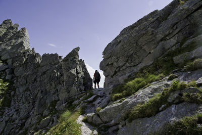 People walking on rocks by mountain against sky