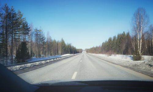 Road amidst trees seen through car windshield