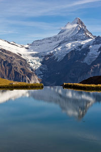 Scenic view of lake by snowcapped mountains against sky