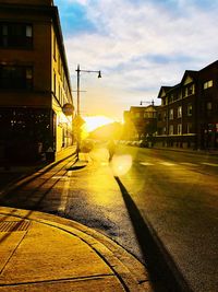 Street amidst buildings against sky during sunset