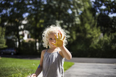 Playful girl showing painted hand while standing in lawn