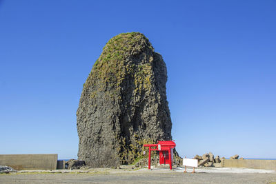 Traditional windmill on rock against clear blue sky