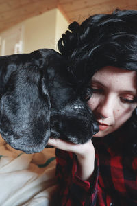 Close-up of thoughtful young woman holding dog on bed at home