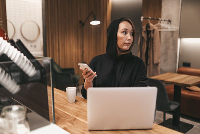 Adult confident business woman freelancer working in a coffee shop cafe using a laptop and phone