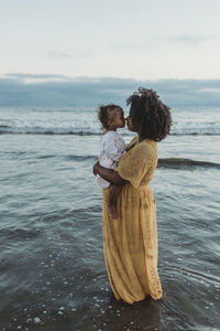 Side view of mother and daughter embracing in the ocean