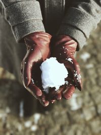 High angle view of person's hands holding snow