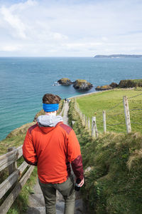 Rear view of man on sea shore against sky