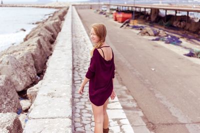 Rear view of woman walking by the beach