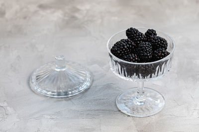 Fresh blackberries in patterned glass bowl on white background