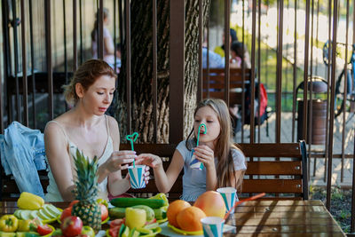 Mother and daughter drinking juice while sitting at restaurant