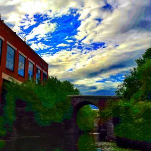 Bridge over river against cloudy sky