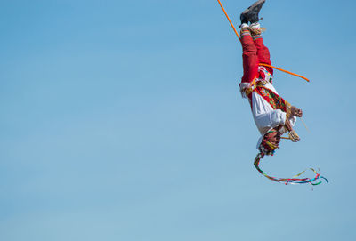 Low angle view of man paragliding against clear blue sky