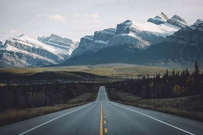 Road leading towards mountains against sky